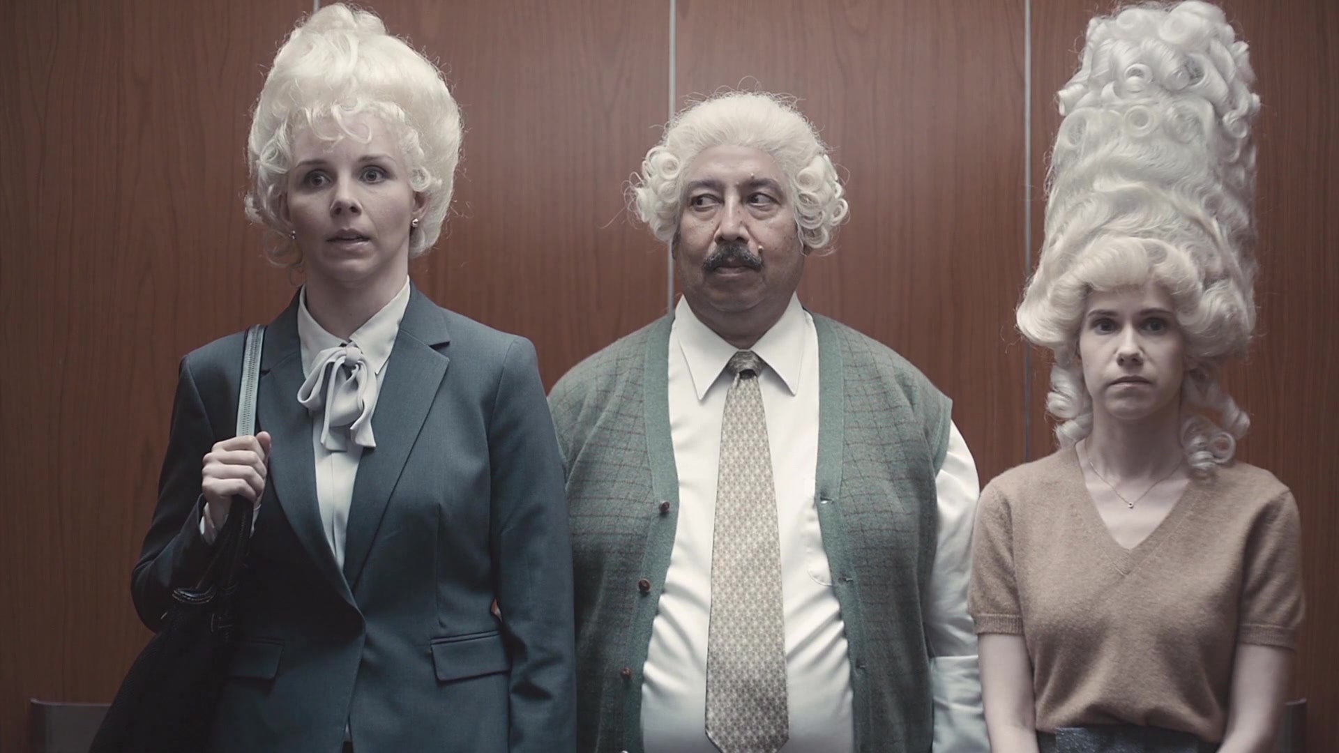 Going Up — three elevator passengers have elaborate white powdered hairstyles